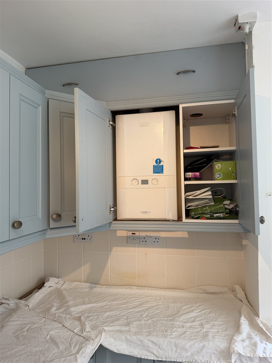 Ideal boiler in a kitchen cupboard before replacement in Epsom
